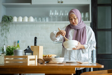 A Muslim woman is preparing to cook breakfast for her family. At the beautiful kitchen in her house, having fun woman with hijab preparing dinner, Islamic woman Enjoying Doing Homemade.