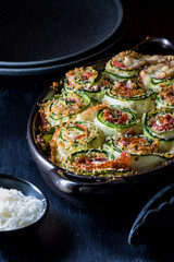 A dish of zucchini rolls ups straight out of the oven with parmesan cheese.