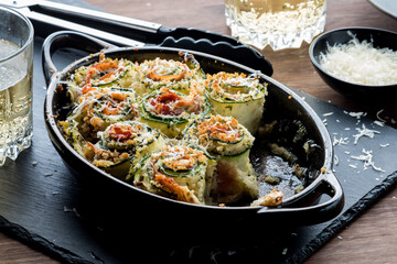 A baking dish of zucchini roll ups with parmesan cheese on top.