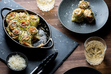 An appetizer of homemade zucchini roll ups with a serving to the side.
