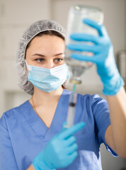 Fototapeta na wymiar Female nurse in mask holding syringe for injection in hospital