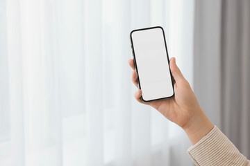 Woman holding smartphone in hand at home, closeup. Space for text