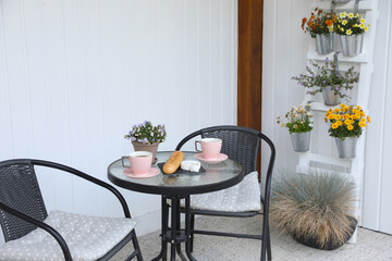 Cups of coffee, potted plant, bread and cheese on glass table. Relaxing place at outdoor terrace