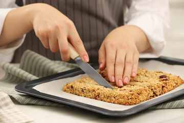 Woman cutting granola bars at table in kitchen, closeup
