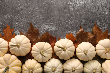 Ripe white pumpkins and dry leaves on grey textured table, flat lay. Space for text