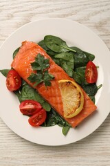 Tasty grilled salmon with tomatoes, lemon and basil on white wooden table, top view