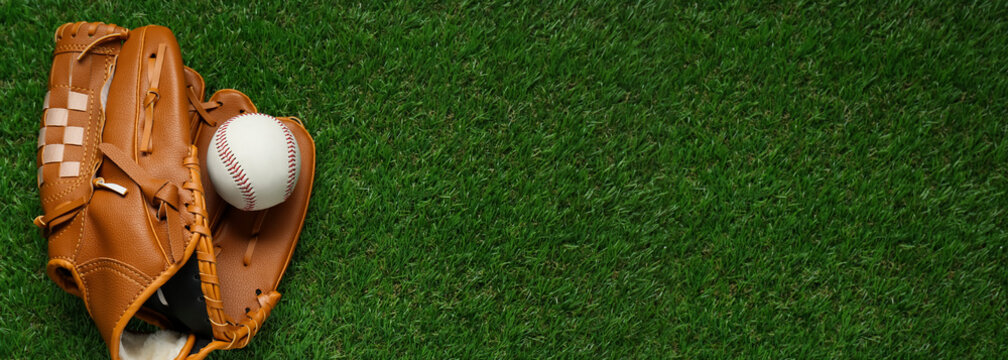 Leather baseball glove and ball on green grass, top view. Banner design with space for text