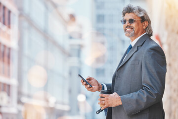 Senior, business man and smartphone in city, travel and commute, bokeh and communication outdoor. Mexican male executive, CEO using phone on journey to work and urban street with mockup space