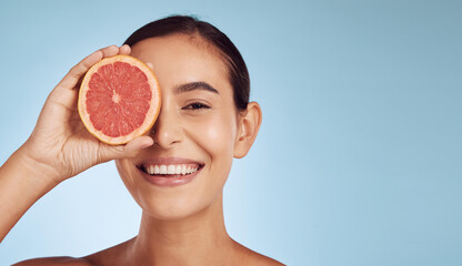 Woman, skincare portrait and grapefruit on eye for beauty, cosmetics and natural product or vitamin c on banner mockup. Face of person or model and red fruit for dermatology on studio blue background