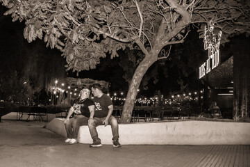 pareja sentada en la noche junto a un árbol