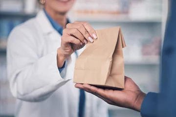 Zelfklevend Fotobehang Woman, pharmacist and hands with medication for patient, healthcare or paper bag at the pharmacy. Closeup of female person or medical professional giving pills, drugs or pharmaceuticals to customer © Azeemud/peopleimages.com
