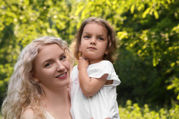 Happy mother with her cute daughter spending time together outdoors, space for text