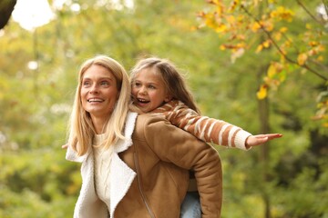 Happy mother having fun with her daughter in autumn park