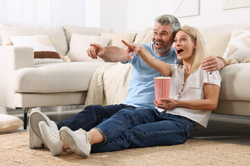 Happy affectionate couple with popcorn spending time together at home. Romantic date