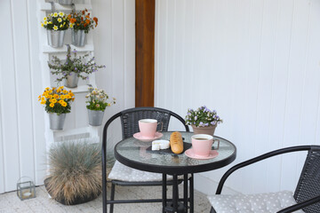Cups of coffee, potted plant, bread and cheese on glass table. Relaxing place at outdoor terrace