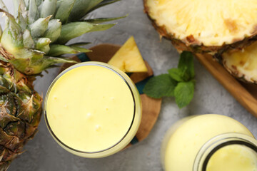 Tasty pineapple smoothie, mint and fruit on grey textured table, flat lay