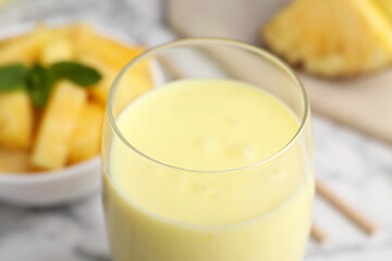 Tasty pineapple smoothie in glass on white table, closeup