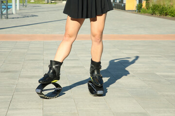 Woman in kangoo jumping boots outdoors on sunny day, closeup