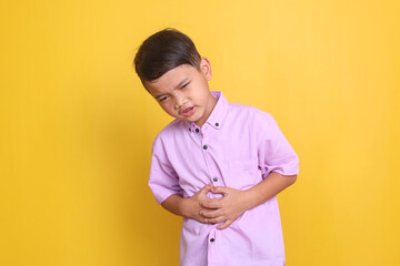 Asian little boy suffering from stomach pain isolated on yellow background