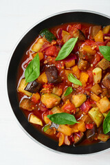Frying pan with tasty ratatouille on white wooden table, top view