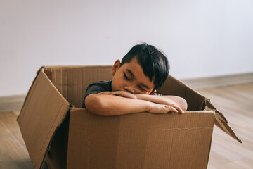Portrait of cute Asian little boy sleeping inside cardboard tired and sleepy
