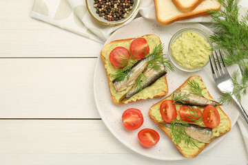 Delicious sandwiches with sprats, tomatoes, dill and avocado puree served on white wooden table, flat lay. Space for text