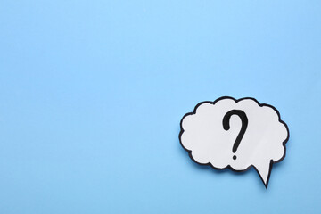 Paper speech bubble with question mark on light blue background, top view. Space for text
