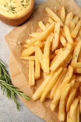 Delicious french fries served with sauce on grey textured table, flat lay