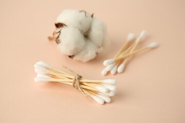 Cotton buds and flower on beige background, closeup