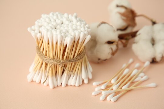 Many cotton buds and flowers on beige background, closeup