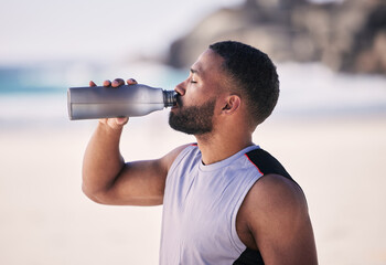 Beach, exercise and man drinking water after running, workout or cardio fitness for health....