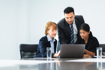 Group of three professional discussing numbers in a business meeting with use laptop. Team of business people brainstorming solutions for a project as they work towards the success of their company.