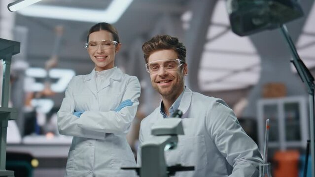 Smiling scientists looking camera in modern laboratory close up. Two researchers