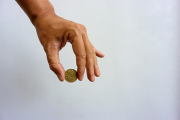 Human hand holding rupiah coin isolated on white background. Collecting, saving, investing or...