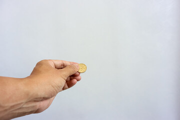 Human hand holding rupiah coin isolated on white background. Collecting, saving, investing or donation concept