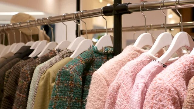Tweed jackets hanging on hangers in female clothing store close-up, side view.