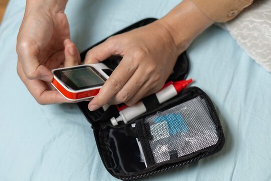 A woman's hand checking her blood sugar level with a glucometer by herself at her home. SHOTLISThealth