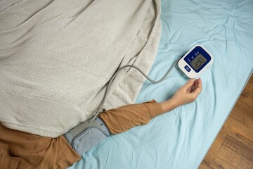 Young woman measuring his blood pressure at home in bed. self blood pressure and heart rate