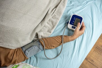Young woman measuring his blood pressure at home in bed. self blood pressure and heart rate