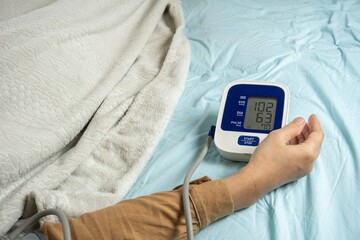 Young woman measuring his blood pressure at home in bed. self blood pressure and heart rate