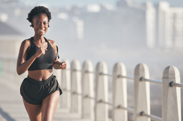 Sports, running and black woman outdoor with music earphones for audio, radio sound and podcast. Smile, fitness and happy African athlete training, workout and exercise for health, wellness or cardio