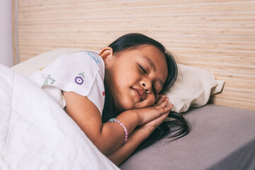 Asian little girl in pajama sleeping in a bedroom.