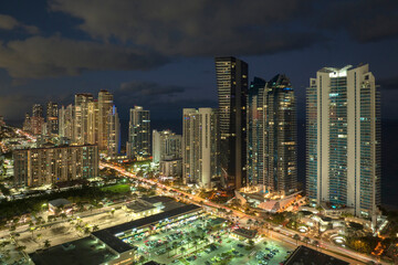 Aerial view of downtown district in Sunny Isles Beach city in Florida, USA. Brightly illuminated high skyscraper buildings in modern american midtown