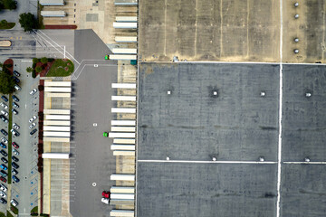 Aerial view of large commercial loading bay with many delivery trucks unloading and uploading retail goods for nationwide distribution. Global economy concept