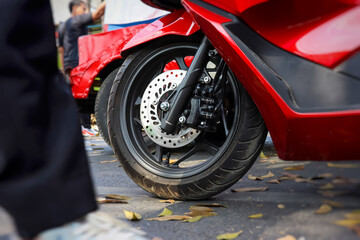 Close up view of front wheel of automatic motorcycle stopped on the asphalt road