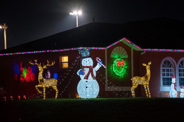 Brightly illuminated Christmas decorations on front yard of Florida family home. Outside decor for...