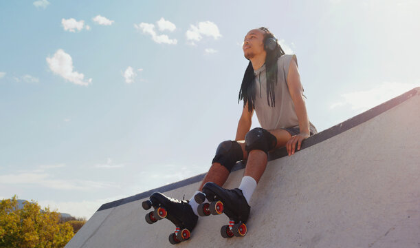 Music, relax and man rollerskating at a park, thinking and sitting in peace in Australia. Freedom, idea and person planning to skate on a ramp with audio from headphones for motivation in nature