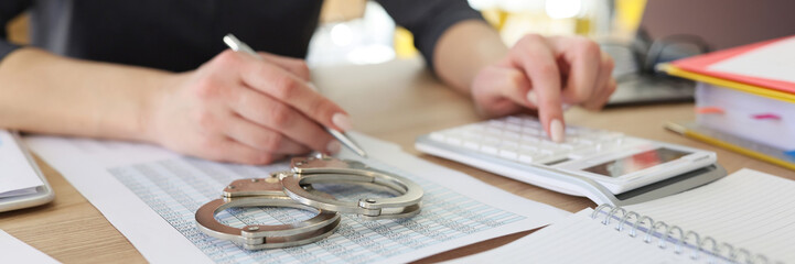 Handcuffs on investigation paper while woman making counts