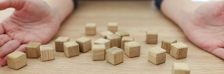 Woman opens palms up sitting near scattered wooden cubes