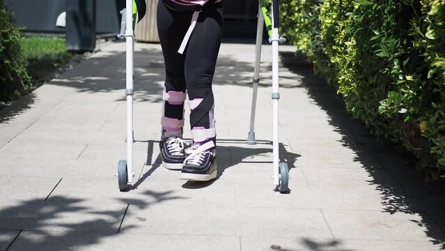  child with walking frame and knee orthosis outdoor 
